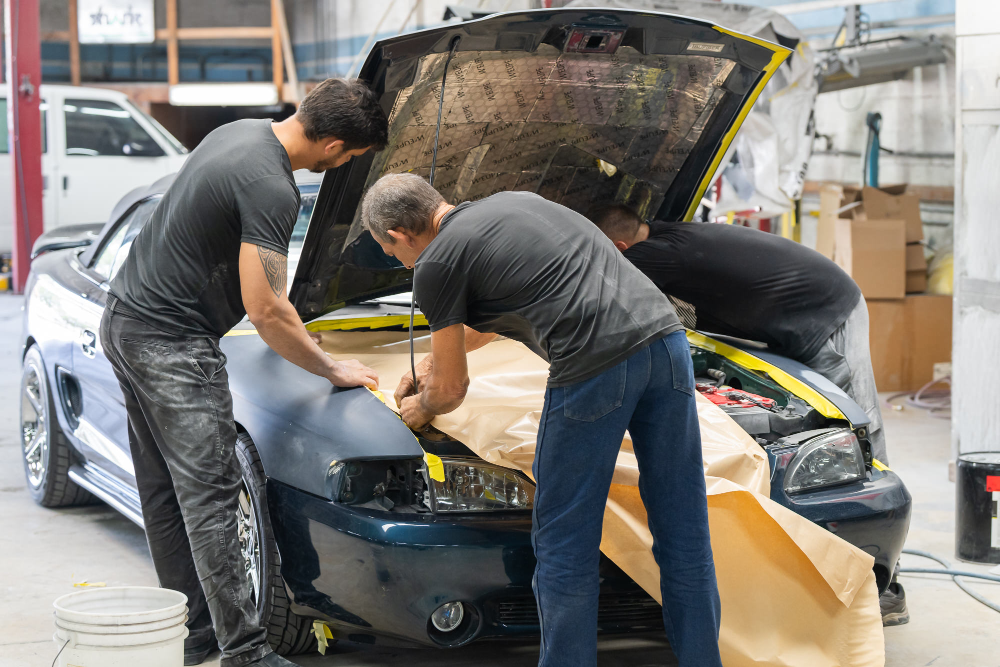 Precision Paint & Body Shop team members collaborating on a vehicle restoration