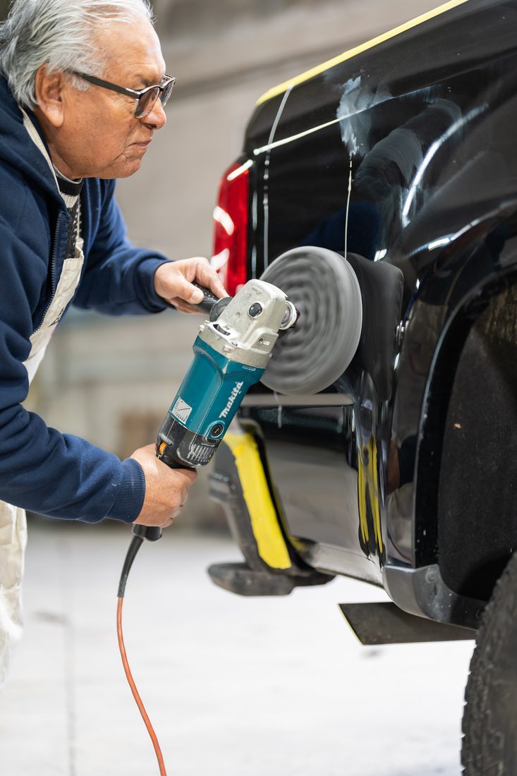 Technician machine-polishing a black panel to level the finish