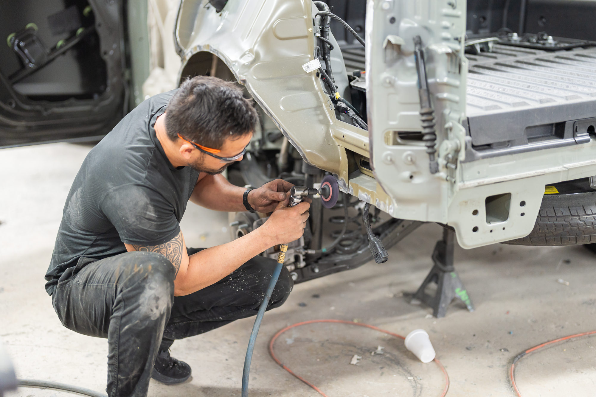 Technician repairing a red sports car bumper at Precision Paint & Body Miami